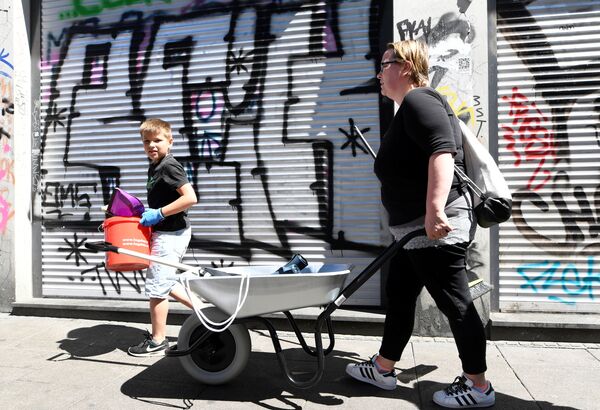 طفل يقوم بتنظيف الشارع مع والدته - سبوتنيك عربي