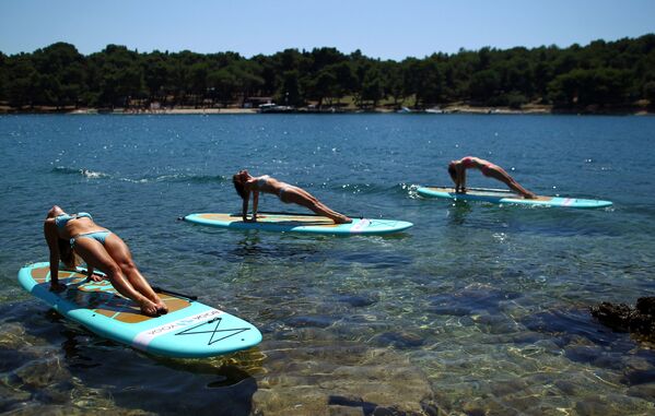 ممارسة اليوغا على ألواح الركمجة في فيروديلا على ساحل البحر الأدرياتيكي، كرواتيا، 10 يوليو/ تموز 2017 - سبوتنيك عربي