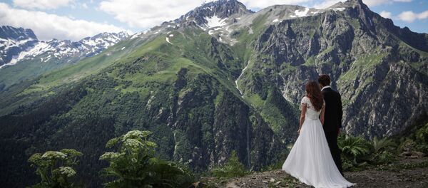 متزوجان حديثا على خلفية منتجع دومباي الجبلي في قراتشاي - تشيركيسيا شمال القوقاز، روسيا الاتحادية - سبوتنيك عربي