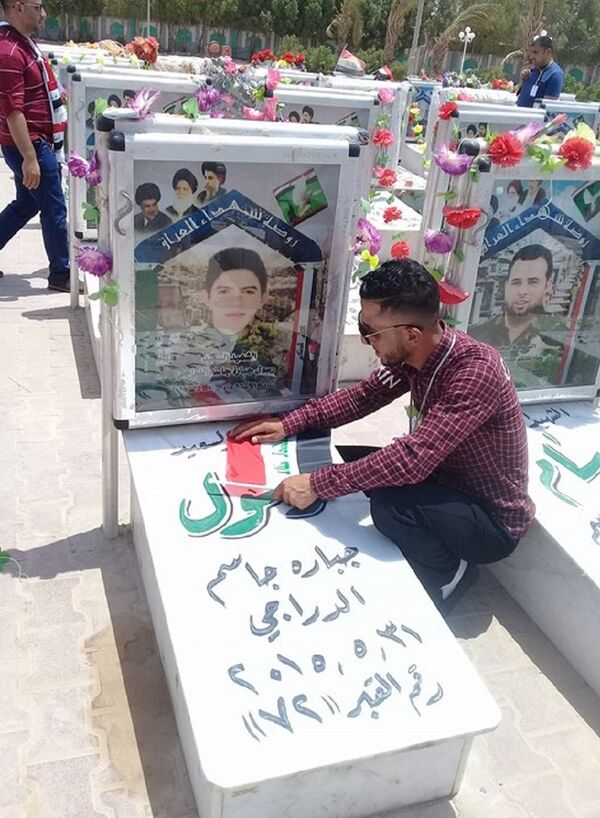 شاب عراقي أمام قبر أحد ضحايا داعش - سبوتنيك عربي