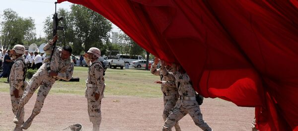 جندي وبندقيته يتعلقان بعلم عملاق عن طريق الخطأ خلال التحضيرات للاحتفال بالذكرى الـ 207 لاستقلال المكسيك عن إسبانيا، والتي تصادف يوم 16 سبتمبر/ أيلول فى سيوداد خواريز، المكسيك فى 4 سبتمبر/ أيلول 2017 - سبوتنيك عربي