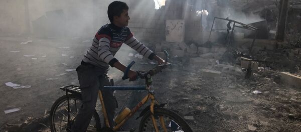 طفل بجانب مبنى مدمر في قطاع غزة - سبوتنيك عربي