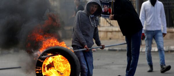 فلسطيني يحمل إطارا مشتعلا خلال المواجهات مع الشرطة الإسرائيلية في بيت لحم، الضفة الغربية، فلسطين 27 ديسمبر/ كانون الأول 2017 - سبوتنيك عربي