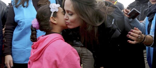 سفيرة الأمم المتحدة للنوايا الحسنة، أنجولينا جولي تقبل طفلة لاجئة سورية، خلال زيارتها لمخيم الزعتري للاجئين السوريين في المفرق شمال الأردن - سبوتنيك عربي