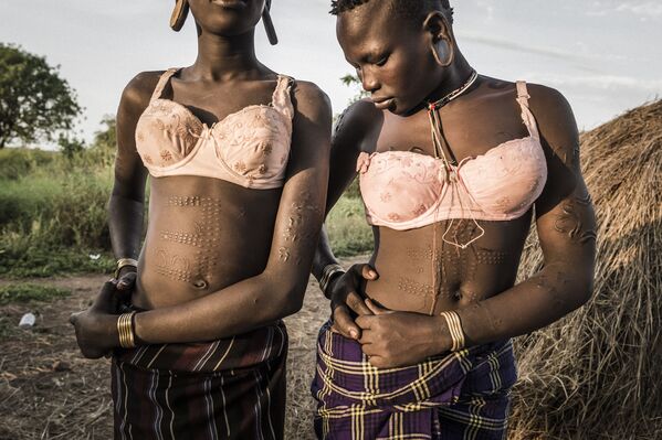 مسابقة صور الصحافة العالمية لعام 2018 - صورة بعنوان تغيير أومو للمصور فاوستو بودافيني، في فئة التصوير مشاريع طويلة الأمد فتاتان تستعدان للرجوع إلى قريتهن بعد تعبئة الدلال بالماء من البئر، إثيوبيا - سبوتنيك عربي