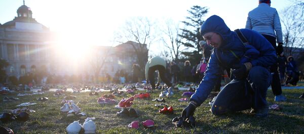 نشطاء يضعون 7000 حذاء على العشب أمام مبنى الكونغرس بالعاصمة الأمريكية واشنطن في 13 مارس/آذار 2018 - سبوتنيك عربي