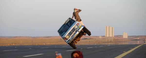 شاب يلتقط صورة سيلفي على خلفية شابين سعوديين يقودان سيارة على عجلتين فقط في تبوك، السعودية 11 مارس/ آذار 2018 - سبوتنيك عربي