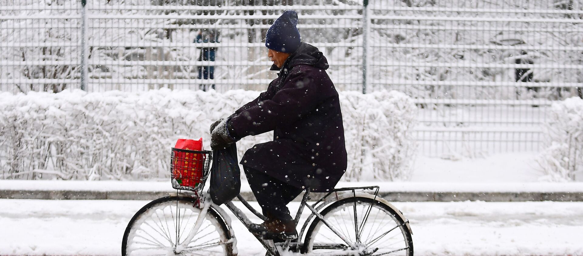 رجل يركب دراجة هوائية خلال تساقط ثلوج كثيفة في شنيانغ، الصين 15 مارس/ آذار 2018 - سبوتنيك عربي, 1920, 11.11.2021