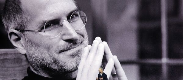 رئيس شركة أبل الأمريكية تيم كوك وفي الخلفية صورة لمؤسس الشركة الراحل ستيف جوبز - سبوتنيك عربي