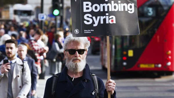 رجل يحمل لافتة توقفوا عن قصف سوريا!، للاحتجاج على الهجمات على سوريا في لندن، إنجلترا - سبوتنيك عربي