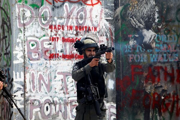 شرطي الحدود الإسرائيلي يطلق الغاز المسيل للدموع على المتظاهرين الفلسطينيين في بيت لحم خلال احتجاجات ضد نقل السفارة الأمريكية إلى القدس عشية الذكرى الـ 70 لـ النكبة، الضفة الغربية، فلسطين 14 مايو/ أيار 2018 - سبوتنيك عربي