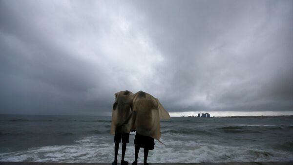 رجلان يحتميان من المطر أمام شاطئ البحر - سبوتنيك عربي