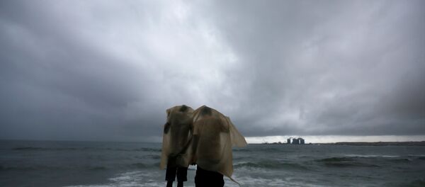 رجلان يحتميان من المطر أمام شاطئ البحر - سبوتنيك عربي