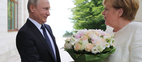 الرئيس فلاديمير بوتين يهدي باقة من الأزهار لمستشارة ألمانيا أنجيلا ميركل لدى وصولها مدينة سوتشي، روسيا 20 مايو/ أيار 2018 - سبوتنيك عربي