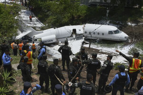 أفراد شرطة طوارئ يتفقدون موقع الحادث، بعد أن انفجرت طائرة على المدرج في مطار تونكونتين الدولي، هندوراس في 22 مايو/ أيار 2018 - سبوتنيك عربي