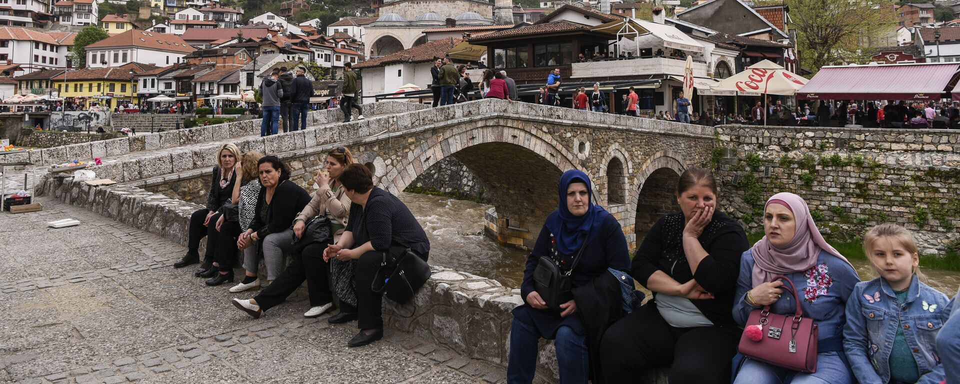 الناس يجلسون بجانب جسر حجري يطل على مدينة بريزرين، كوسوفو - سبوتنيك عربي, 1920, 16.12.2022