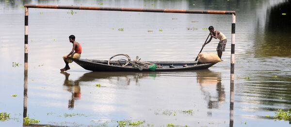 القرويون الهنود المتضررون من الفيضانات يمرون في مراكبهم بجوار مرمى مغممور جزئيا في قرية موكاتا، على بعد 70 كم من جواهاتي، الهند 11 يوليو/ تموز 2013 - سبوتنيك عربي