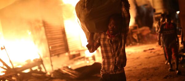 رجل يحمل حقيبة من البضائع أثناء حريق في السوق في بورت-أو-برنس، هايتي 12 يونيو/ حزيران 2018 - سبوتنيك عربي