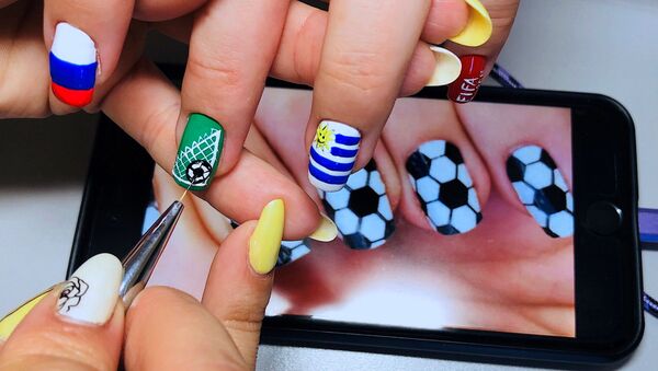 رسامة المناكير ترسم على اظافر فتاة أخرى أعلام المنتخبات، بمناسبة بطولة كأس العالم لكرة القدم 2018 في سامارا - سبوتنيك عربي