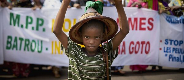 صبي من فولاني يقف أمام لافتة كتب عليها أوقفوا الإبادة الجماعية، خلال مسيرة صامتة نظمتها حركة من أجل السلام (Mouvement Peul et allies pour la paix)، وهي منظمة تضم شعبًا من أصل فولاني في مالي، كرد على المجزرة التي وقعت في كوماغا، في 30 يونيو/ حزيران 2018 - سبوتنيك عربي