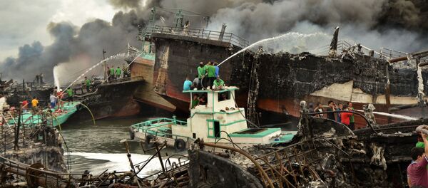 عمال إندونيسيون ورجال الإطفاء يخمدون حريق على قوارب الصيد في ميناء بينوا في دنباسار، في جزيرة بالي، إندونيسيا 9 يوليو/ تموز 2018 - سبوتنيك عربي