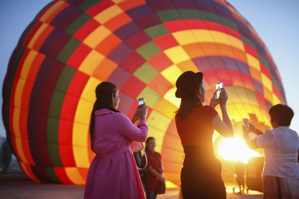 سياح يلتقطون صورا للمنطاد قبل انطلاقه  في رحلة في كابادوكيا، تركيا - سبوتنيك عربي