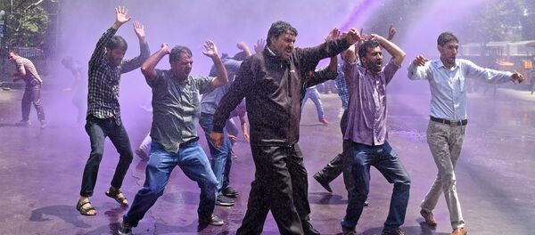 معلمون كشميريون يحتجون بشعارات مناهضة للحكومة بينما تفصلهم الشرطة الهندية بالمياه الملونة الأرجوانية خلال احتجاج في سريناجار في 9 أغسطس/ آب 2018 - سبوتنيك عربي