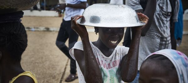 فتاة تقف مع وعاء معدني فوق رأسها على هامش احتجاجات ضد الرئيس المالي الحالي في باماكو في 11 أغسطس/ آب2018 ، عشية الجولة الثانية من الانتخابات الرئاسية في مالي. - سبوتنيك عربي