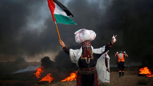 امرأة تحمل علم فلسطين خلال احتجاجات تدعو لرفع الحصار الإسرائيلي عن قطاع غزة، والمطالبة بحق العودة، على الحدود بين القطاع وإسرائيل، شرق مدينة غزة، 14 سبتمبر/ أيلول 2018 - سبوتنيك عربي
