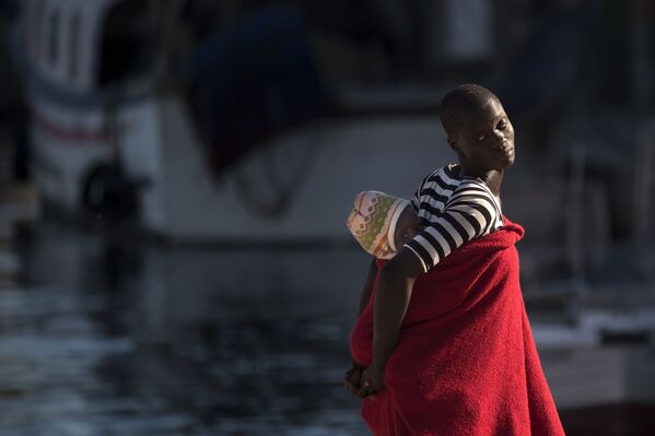 لاجئة تحمل طفلها على ظهرها في ميناء مالقة، إسبانيا 23 سبتمبر/ أيلول 2018 - سبوتنيك عربي