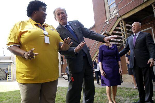 الرئيس الأمريكي السابق جورج بوش الابن يرقص خلال أداء لفرقة موسيقية في إطار زيارته لمدرسة الثانوية وارن إستورن تشارتر في نيو أورليانز، 28 أغسطس/ آب 2015 - سبوتنيك عربي