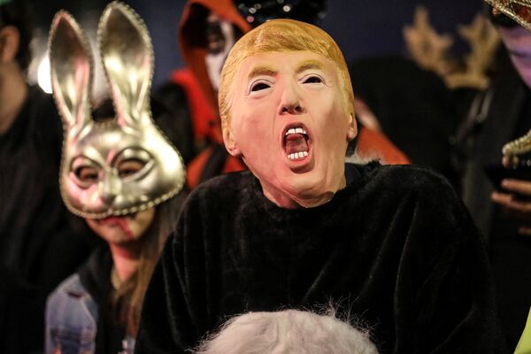 مشاركون في إحتفالات الهالوين في أمريكا يرتدون قناع الرئيس الأمريكي دونالد ترامب - سبوتنيك عربي