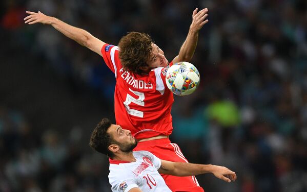 اللاعب التركي هاكان تشالهان أوغلو والروسي ماريو فرنانديز في مباراة لبطولة دوري الأمم الأوروبية  بين منتخبي روسيا وتركيا - سبوتنيك عربي