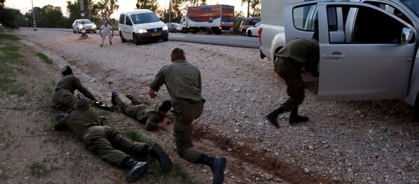 جنود ومدنيون إسرائيليون يحتمون بعد أصوات صفارات الإنذار الجوية على طريق في الجانب الإسرائيلي من الحدود مع غزة - سبوتنيك عربي