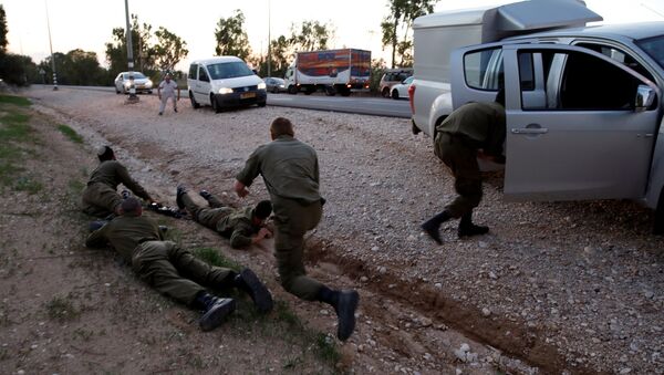 جنود ومدنيون إسرائيليون يحتمون بعد أصوات صفارات الإنذار الجوية على طريق في الجانب الإسرائيلي من الحدود مع غزة - سبوتنيك عربي