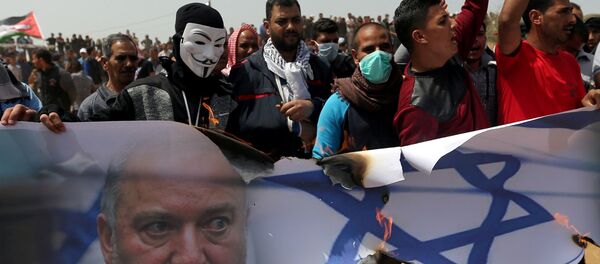 متظاهرون فلسطينيون يحرقون صورة لعلم إسرائيلي ووزير الدفاع الإسرائيلي أفيغدور ليبرمان خلال مظاهرة في جنوب قطاع غزة - سبوتنيك عربي