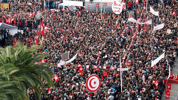 يحمل الناس أعلامًا وهم يحتجون على رفض الحكومة رفع الأجور في تونس العاصمة - سبوتنيك عربي