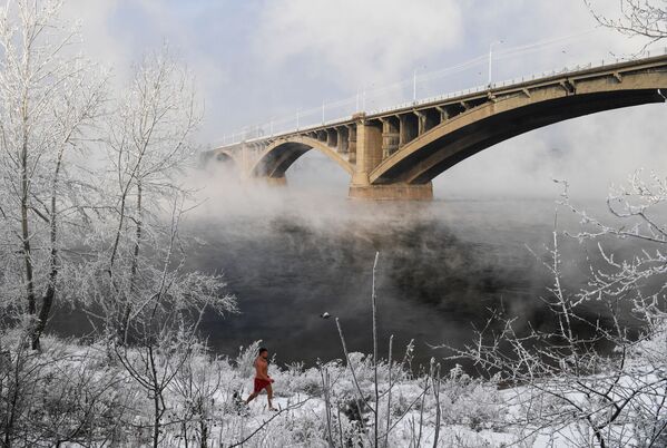 أحد أعضاء نادي كريوفيل للسباحة الشتوية يسير عليى خلفية جسر كومونالني - سبوتنيك عربي
