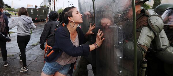 ناشطة من عشيرة مابوتشي تحاول وقف حركة عناصر الشرطة، أثناء مظاهرات في سانتياغو، تشيلي 14 ديسمبر/ كانون الأول 2018 - سبوتنيك عربي