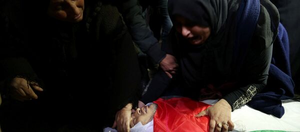 إحدى أقارب كرم فياض وهي تنظر إلى جثمانه خلال جنازته في جنوب قطاع غزة - سبوتنيك عربي