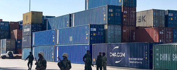 جنود يرافقون مسؤولين حكوميين يقومون بجولة في محطة الحاويات في ميناء عدن - سبوتنيك عربي