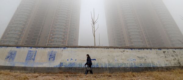 امرأة ترتدي قناعا وتسير وسط المباني في يوم ملوث في إحدى مقاطعات الصين - سبوتنيك عربي