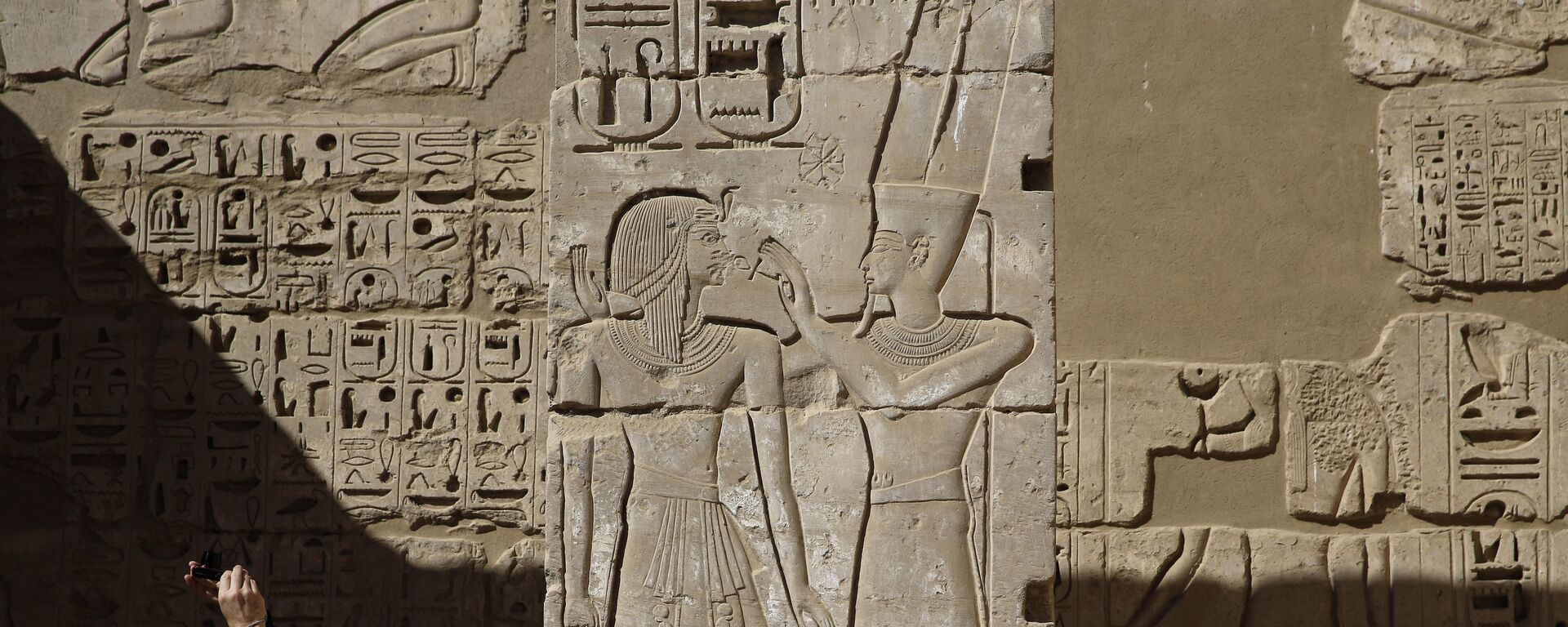 سائح يلتقط صورة لنقوش على معبد رمسيس الثالث في الأقصر - سبوتنيك عربي, 1920, 04.10.2025