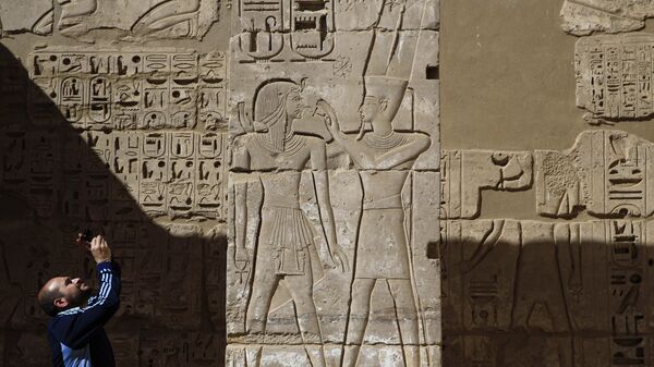 سائح يلتقط صورة لنقوش على معبد رمسيس الثالث في الأقصر - سبوتنيك عربي
