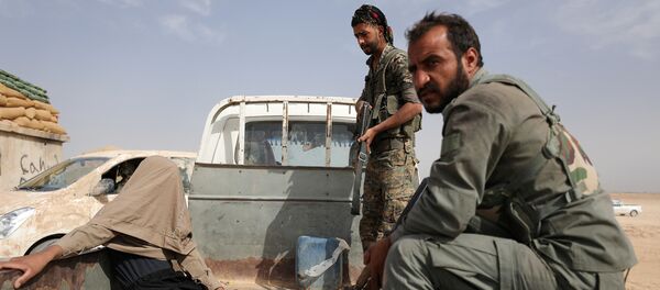 مقاتلون من قوات سوريا الديمقراطية بعد القبض على جريح أثناء قتالهم مع داعش في المنطقة الشمالية من دير الزور في سوريا - سبوتنيك عربي
