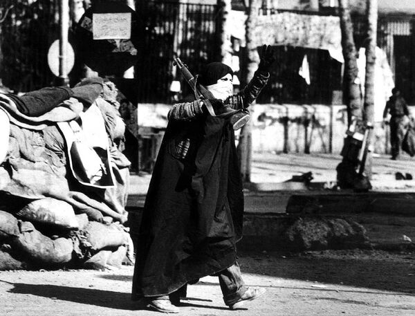 امرأة إيرانية تلوح بعلامة النصر وهي تحمل بندقية في طهران أثناء ثورة البلاد في فبراير/ شباط 1979 - سبوتنيك عربي