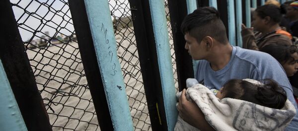 مهاجر يحمل ولده على الحدود بين المكسيك وأمريكا مهاجر يحمل ولده على الحدود بين المكسيك وأمريكا - سبوتنيك عربي