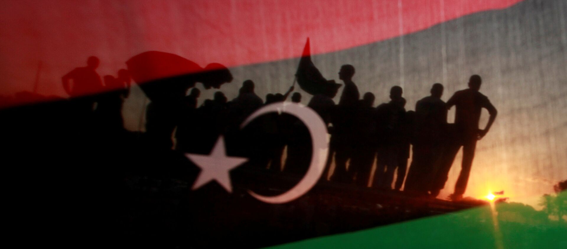 ليبيون يظهرون من خلال علم مملكة ليبيا خلال مسيرة الاحتفال أمام مقر القذافي في مجمع باب العزيزية في طرابلس - سبوتنيك عربي, 1920, 09.02.2021