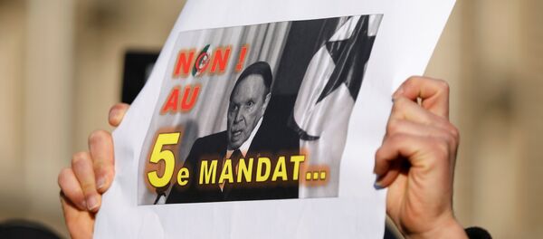 أحد المتظاهرين يحمل لافتة خلال احتجاج ضد الرئيس عبد العزيز بوتفليقة الذي يسعى لولاية خامسة في الانتخابات الرئاسية - سبوتنيك عربي