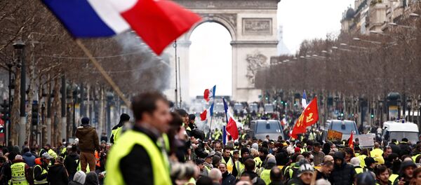 أحد المتظاهرين يرتدي سترة صفراء يلوح بعلم فرنسي وهو يقف على الشانزليزيه بالقرب من قوس النصر أثناء مظاهرة حركة السترات الصفراء في باريس - سبوتنيك عربي